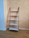 Ein leeres Leiterregal steht in einer Ecke auf einem Holzboden.