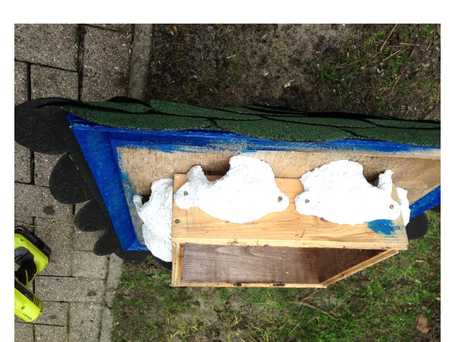 Holzrahmen mit Dachpappe und Figuren