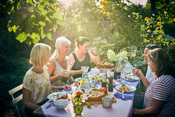 Eine Gruppe von Personen isst gemeinsam an einem Tisch im Garten.
