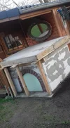 Ein im Bau befindlicher, gemauerter Ofen vor einer Holzhütte im Garten.