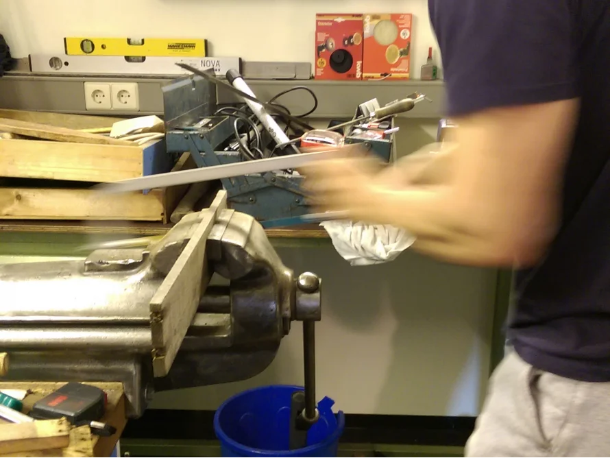 Person sägt Metall mit einer Bügelsäge