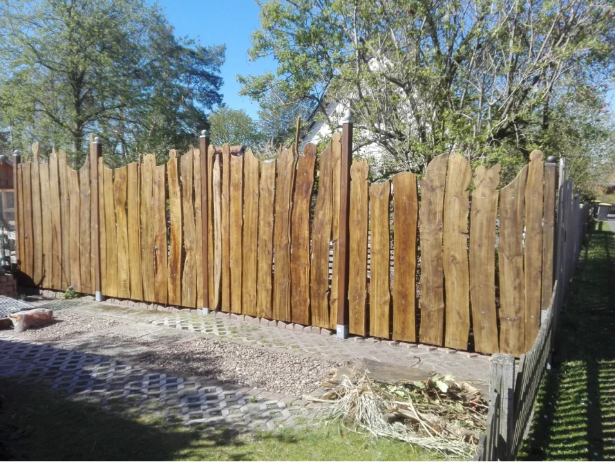 Hölzerner Gartenzaun mit unregelmäßigen Brettern