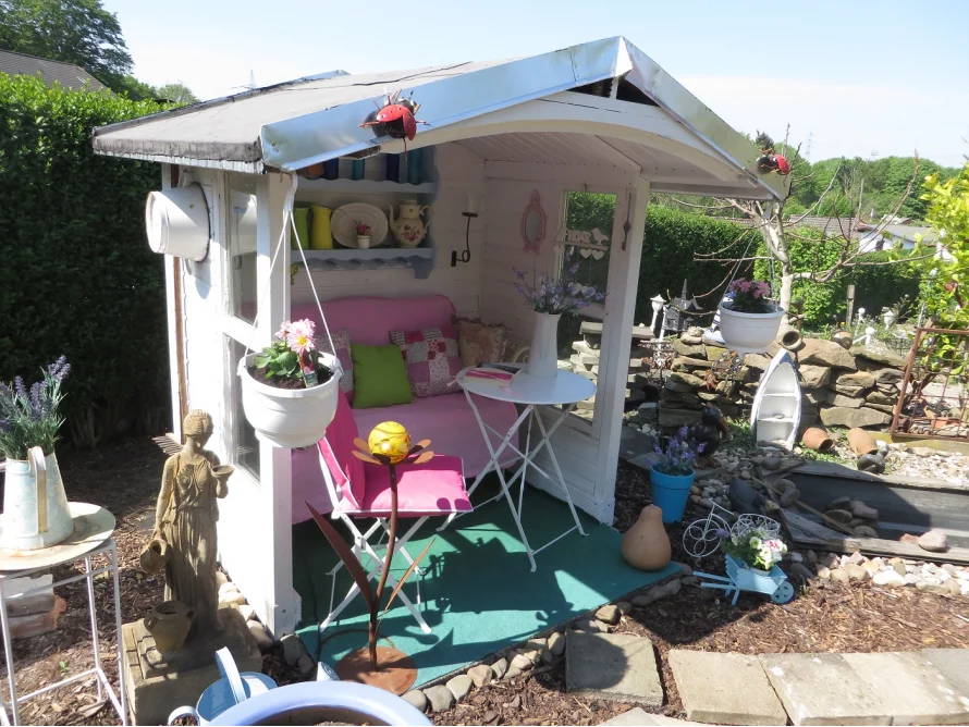 Gemütliches, weißes Gartenhaus mit Dekoration