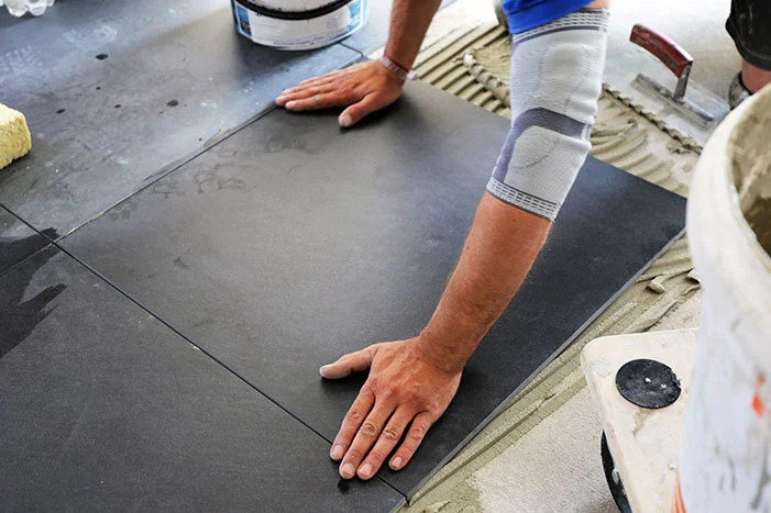 Person verlegt schwarze Fliesen
