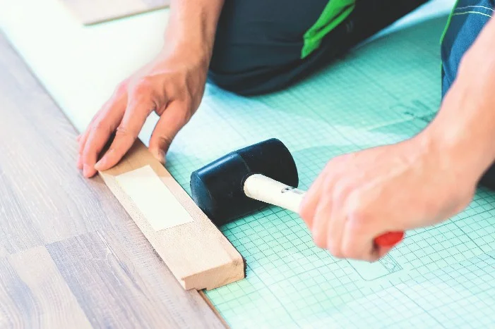 Person verlegt Laminat mit Gummihammer