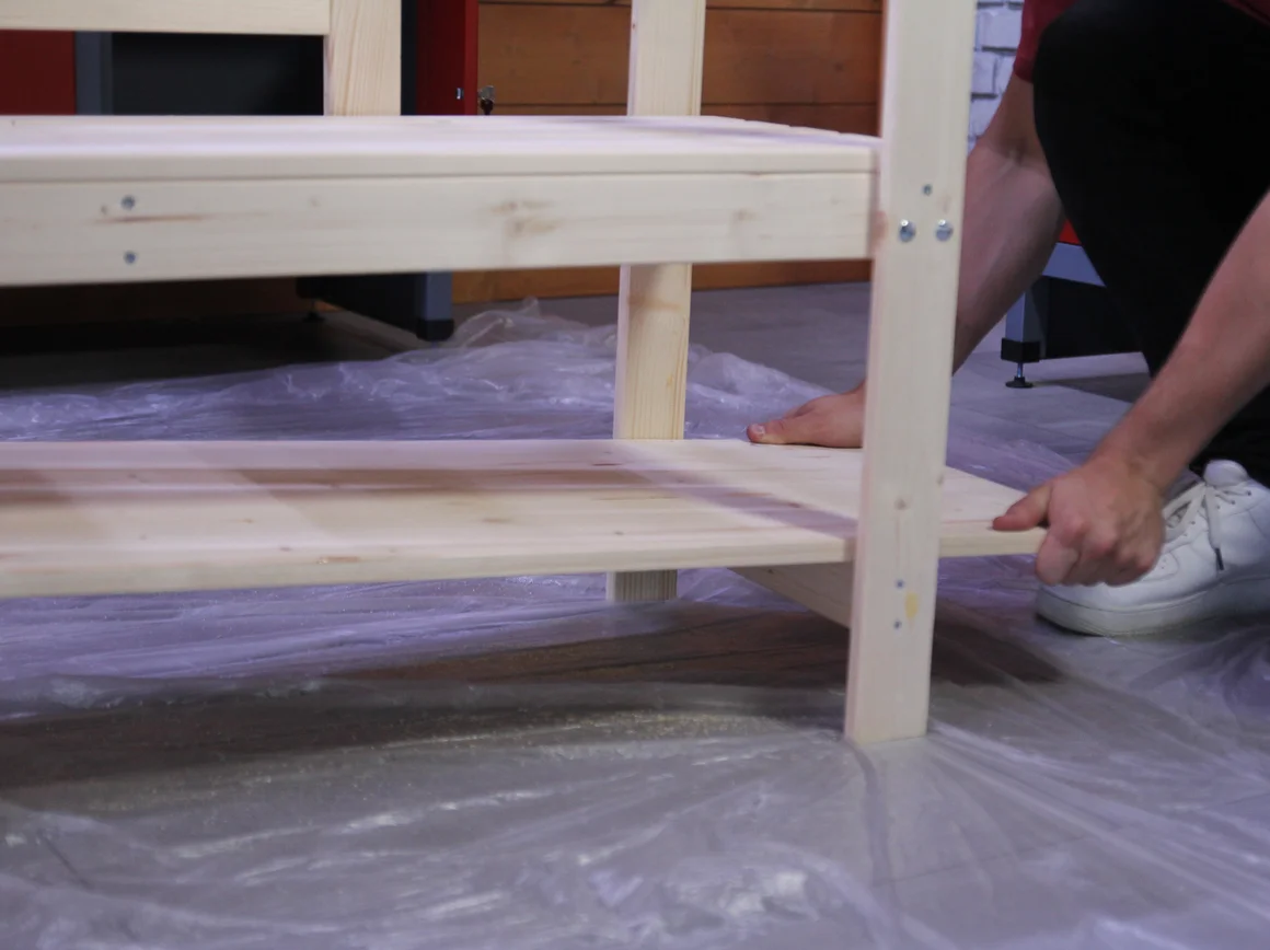 Person baut Holzregal zusammen