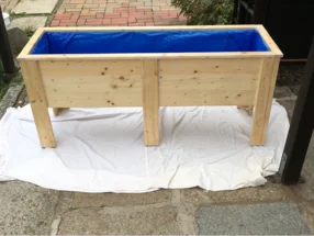 Hölzerner Blumenkasten mit blauer Folie ausgelegt