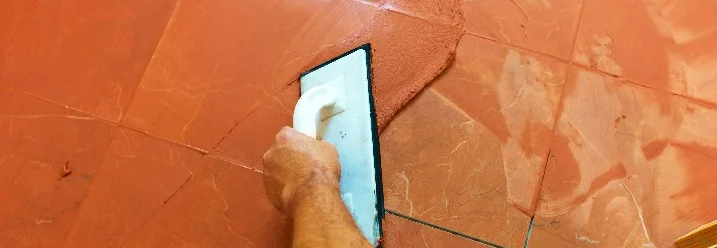 Person verfugt Fliesen mit Kelle