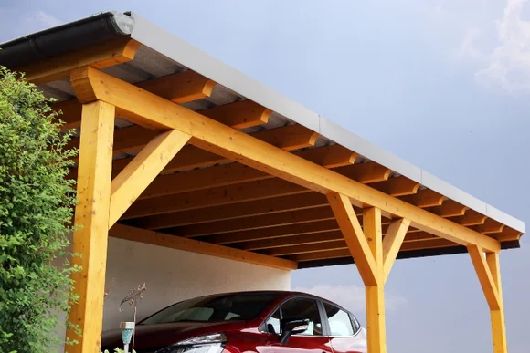 Holzcarport mit einem roten Auto darunter