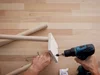 Person verschraubt Holzbeine mit Akkuschrauber an Holzplatte