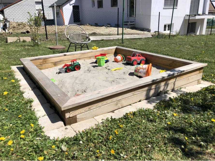 Sandkasten aus Holz mit Spielzeug