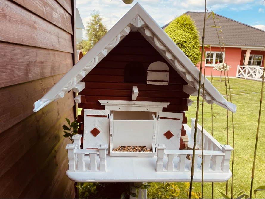 Ein Vogelfutterhaus aus Holz im Stil eines Chalets.