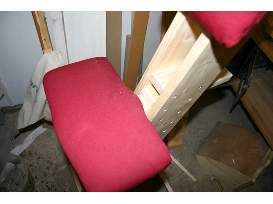 Holzgestell eines knienden Stuhls mit rotem Polster