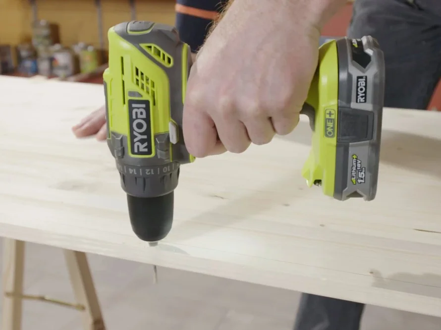 Person verschraubt Holzbrett mit Akkuschrauber