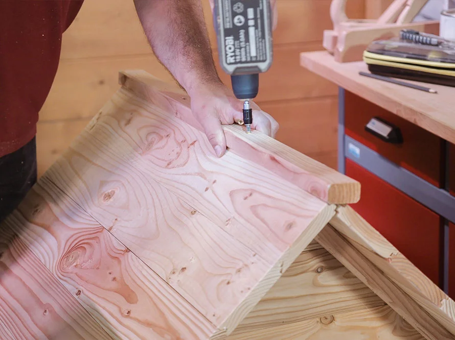 Person verschraubt Holzbretter mit Akkuschrauber