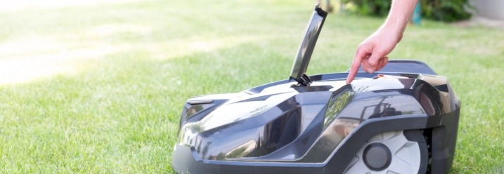 Person startet Mähroboter