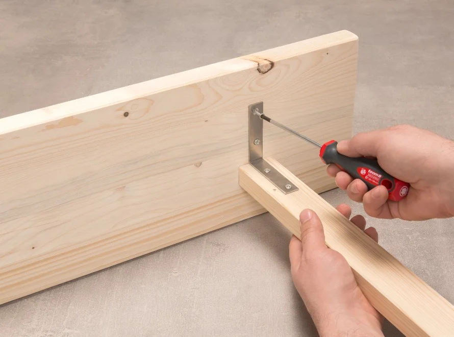 Person schraubt Holzbrett fest.