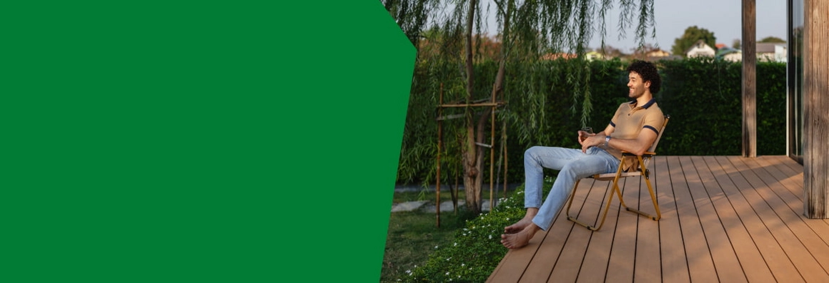 Eine Person entspannt sich auf einem Stuhl auf einer Holzterrasse.