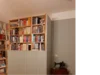 Ein Bücherregal mit einer Nähmaschine daneben.