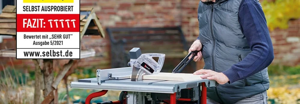 Person sägt mit einer Tischkreissäge ein Stück Holz.