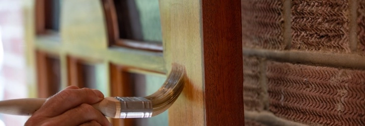 Lasur wird mit Pinsel auf Haustür verteilt.