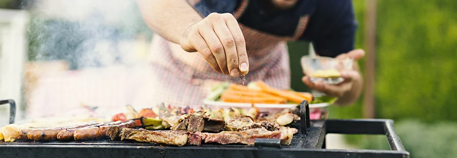 Person würzt Grillgut