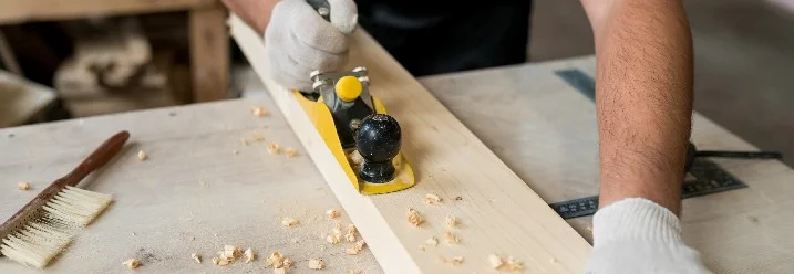 Person hobelt Holzbrett