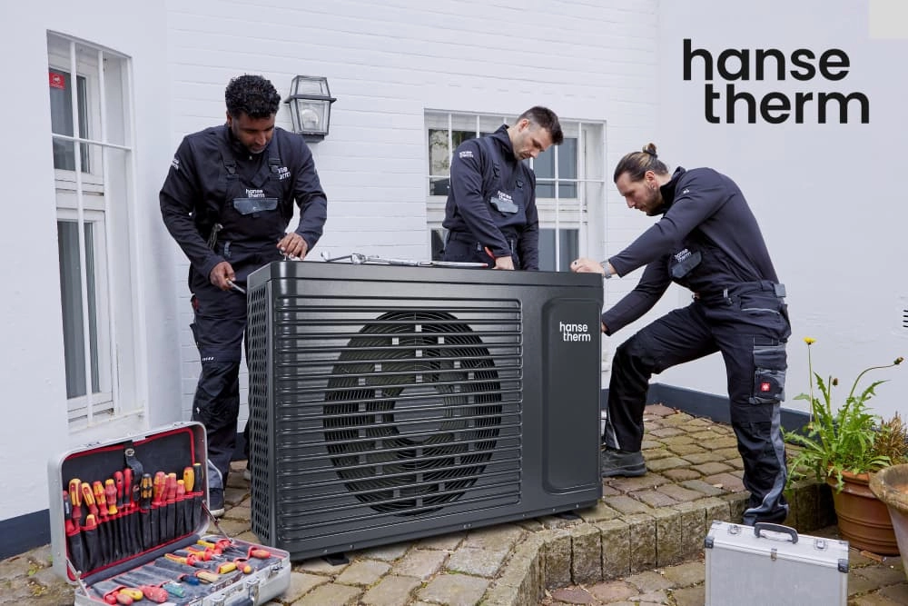 Drei Personen installieren eine Wärmepumpe. Das Logo der Marke hansetherm ist abgebildet.