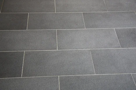 Grauer Fliesenboden mit rechteckigen Fliesen.