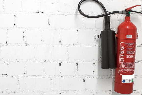 Roter Feuerlöscher an weißer Ziegelwand