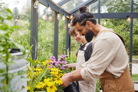 Mann und Frau kümmern sich um Blumen in Gewächshaus