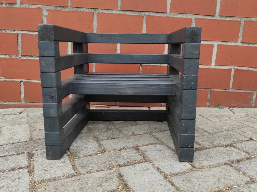 Schwarzer Holzstuhl vor Backsteinwand