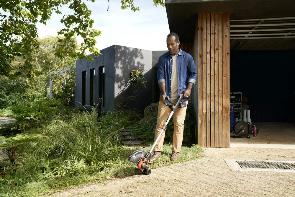 Person trimmt Rasenkante mit Rasentrimmer