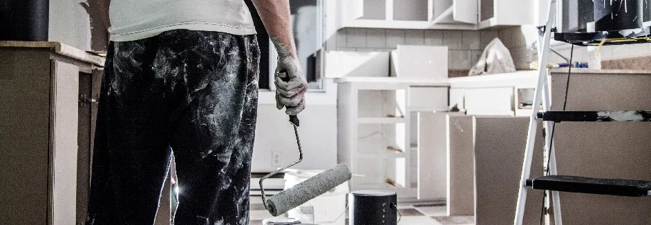 Person mit Farbrolle in renovierter Küche