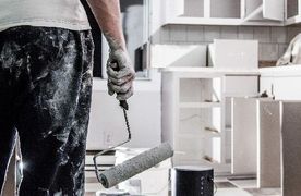 Mann mit Malerrolle renoviert Küche