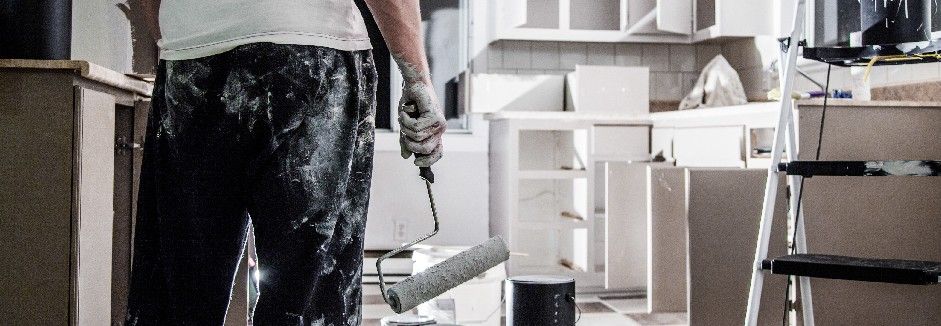 Mann mit Malerrolle renoviert Küche