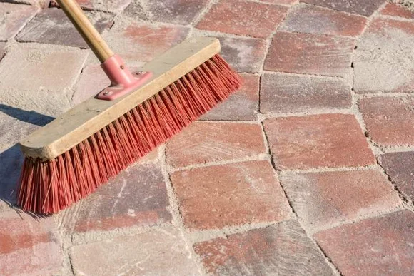 Besen reinigt Pflastersteine