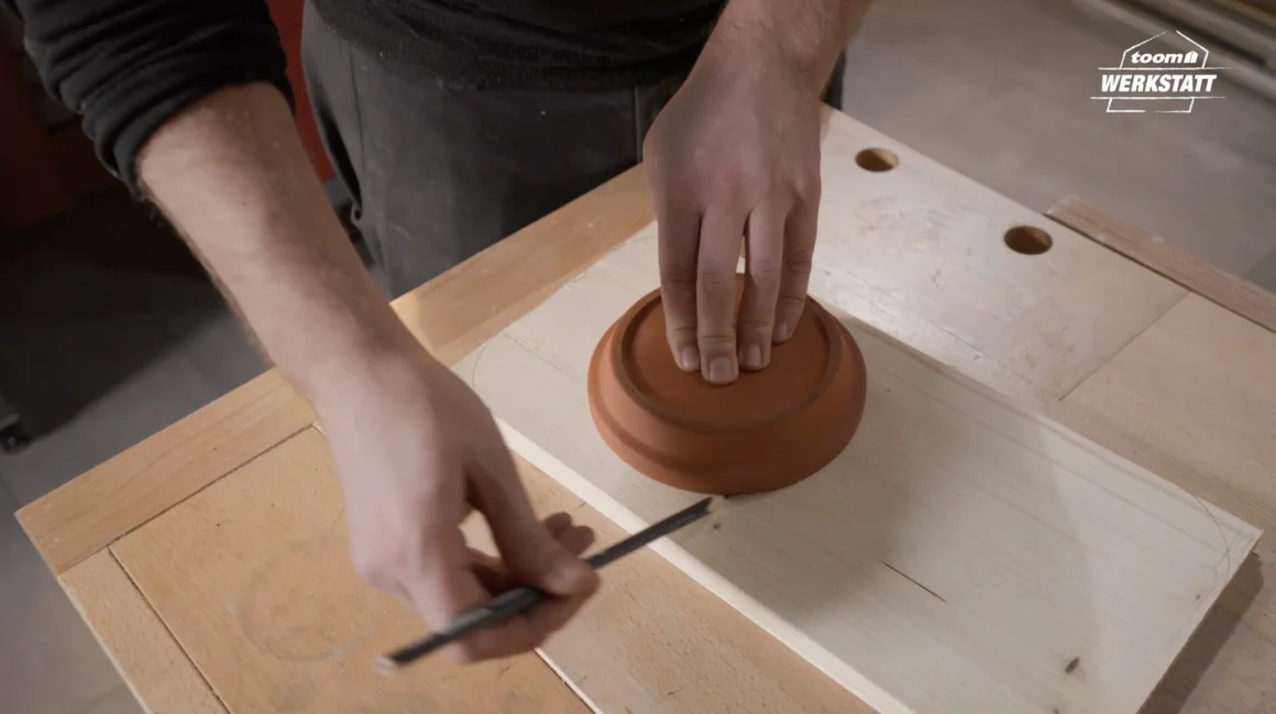 Person zeichnet Kreis auf Holzbrett