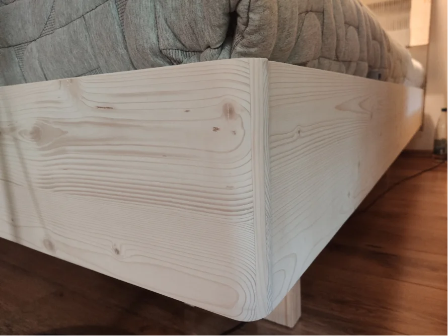 Ecke eines Bettgestells aus hellem Holz