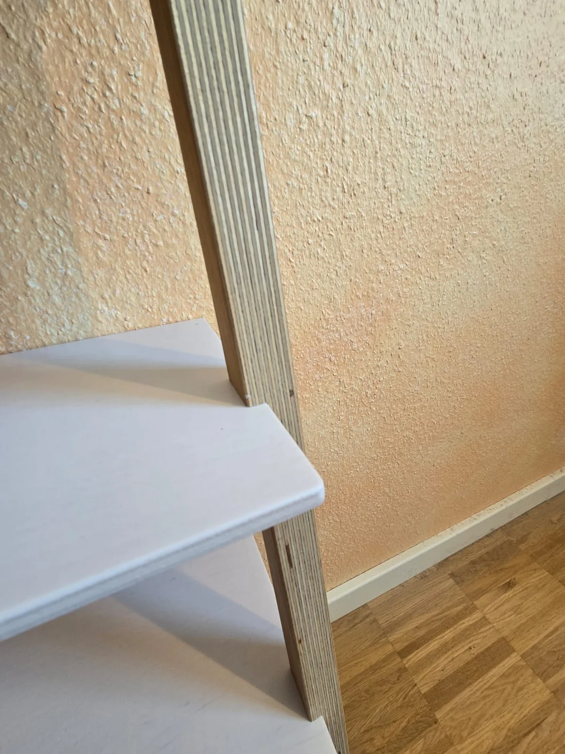 Nahaufnahme eines Regals aus Schichtholz mit weißen Brettern