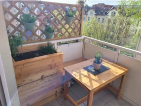 Sonniger Balkon mit Holzmöbeln und Pflanzen