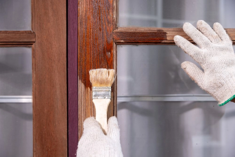 Person lasiert Fenster