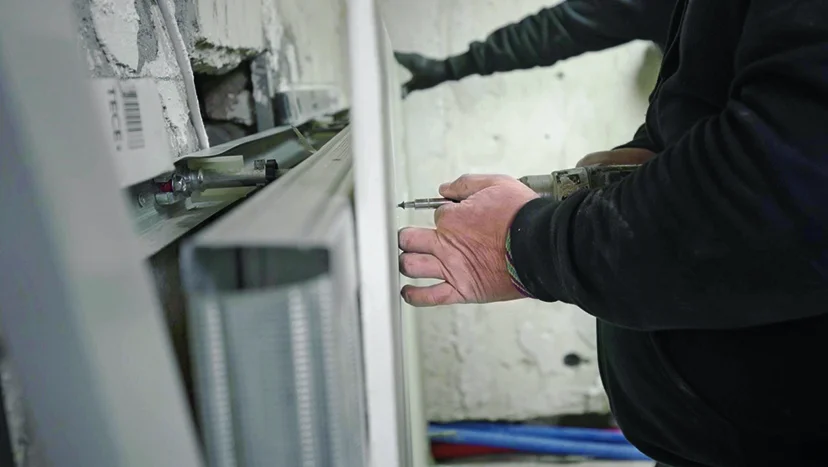 Person befestigt Metallrahmen an Wand