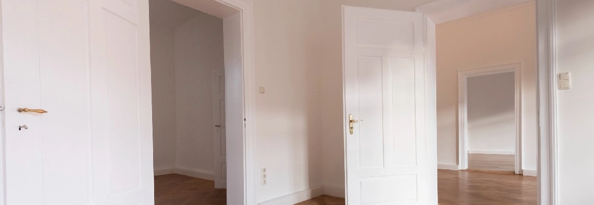Leere Wohnung mit weißen Türen und Parkettboden