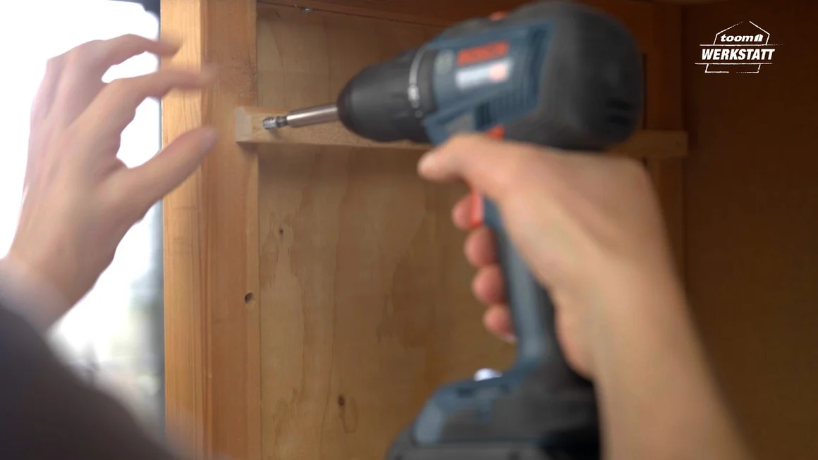 Person schraubt Holzbrett mit Akkuschrauber fest