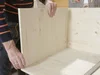Person baut Holzkiste zusammen