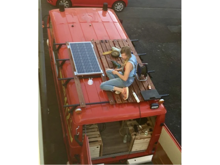 Person montiert Solarpanel auf Transporterdach