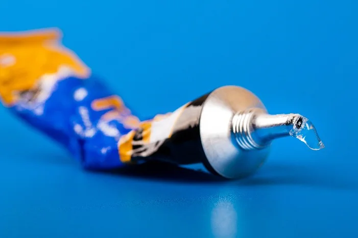 Tube mit Klebstoff auf blauem Grund