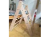 Ein Kletterdreieck aus Holz steht auf einem Holzboden in einem Zimmer.