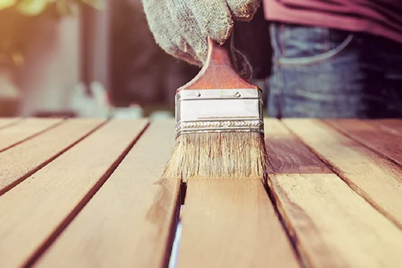 Person streicht Holz mit Pinsel